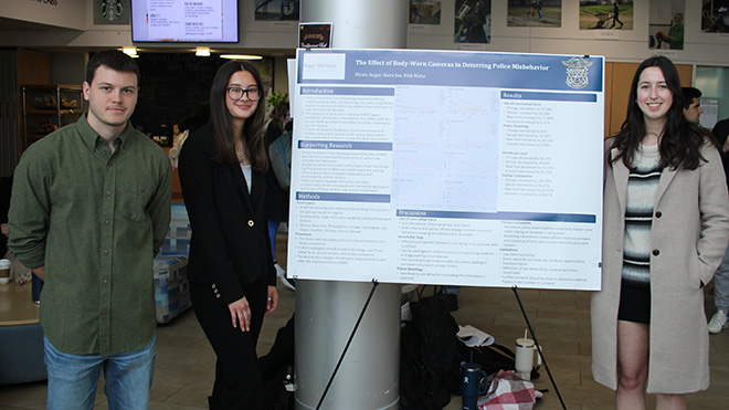 Three students with their research poster on body-worn cameras