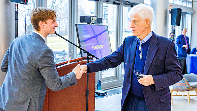 First-year student Sam Carter shakes hands with Mario Gabelli in GHH