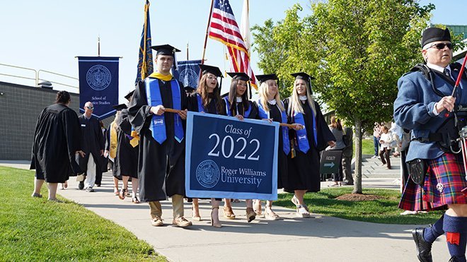 Graduates march in with Class of 2022 processional banner.