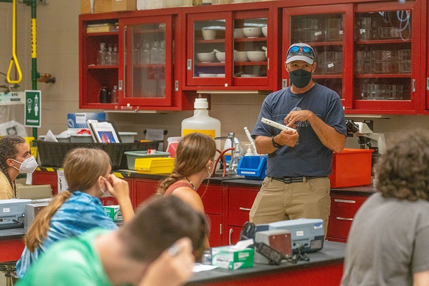 Brian Wysor explaining lab equipment to a group of high school students. 