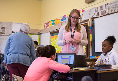 Education student leads a small group lesson with students using laptops in a classroom.