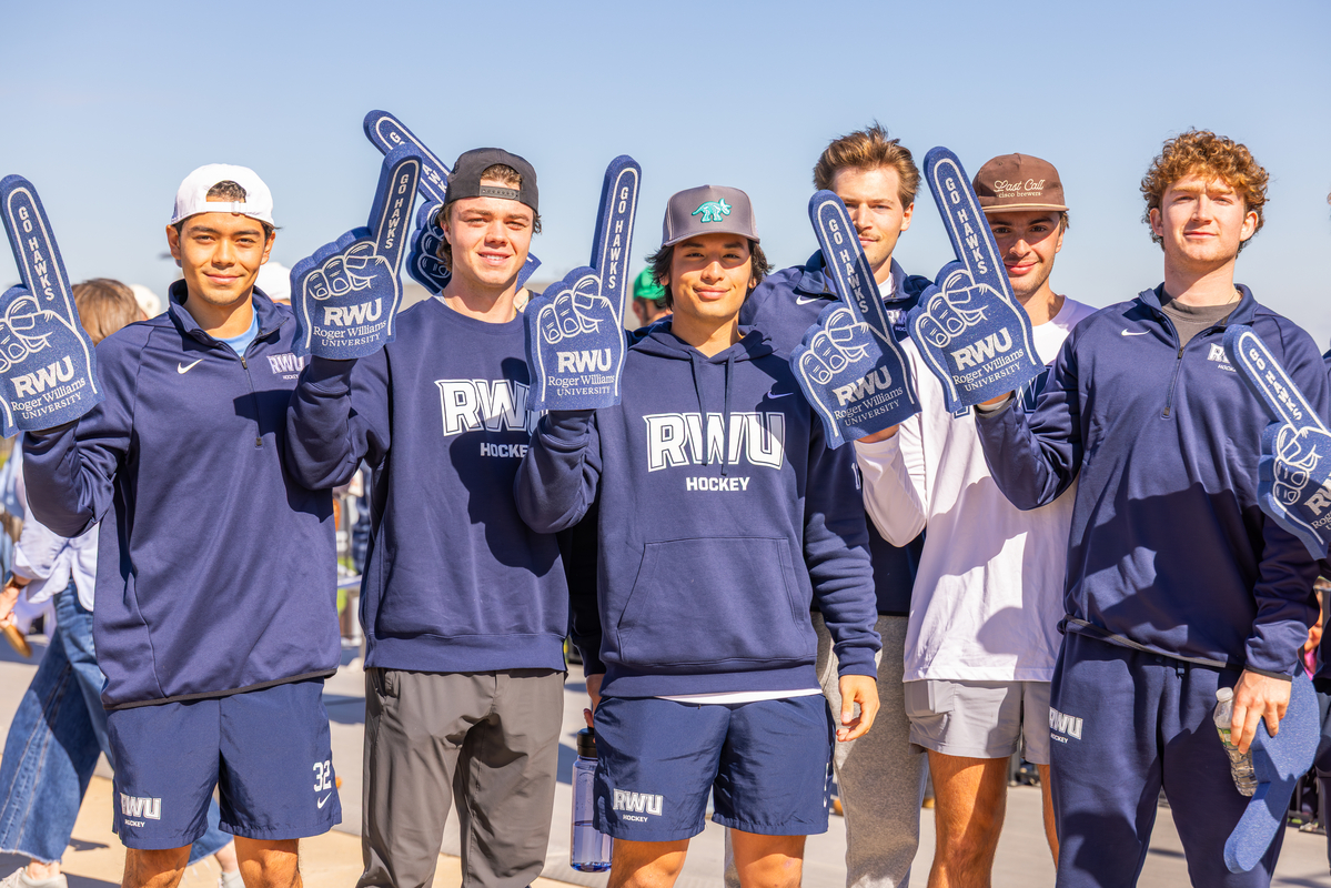 Hawks show their Roger pride, foam fingers held high as they cheer on RWU student-athletes during Homecoming and Family Weekend.