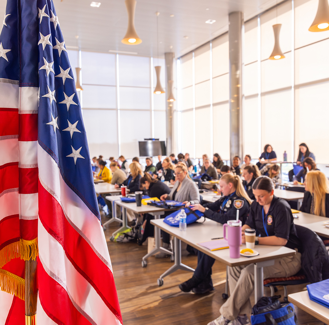 An American flag stands in front of a classroom filled with conference attendees