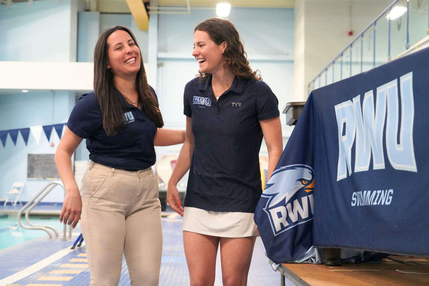 Assistant Coaches Joanna Tchobanova and Noelle Schneider share a laugh on the pool deck at RWU’s Campus Recreation Center.