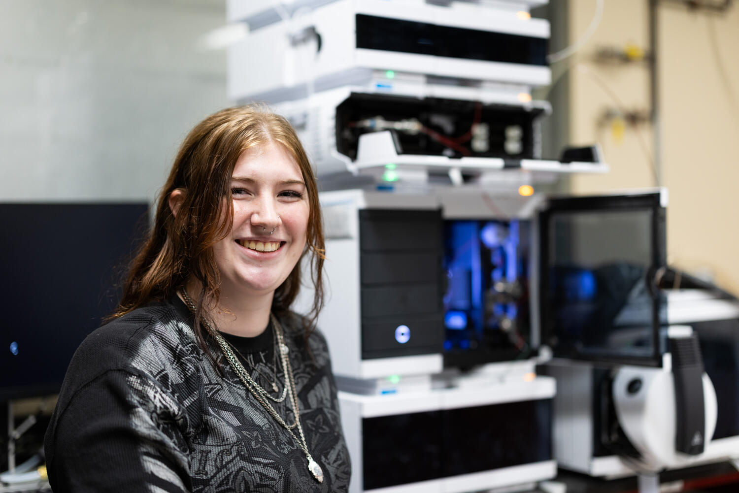 Senior Mackenzie Marshall stands beside the liquid chromatography/mass spectrometry equipment.