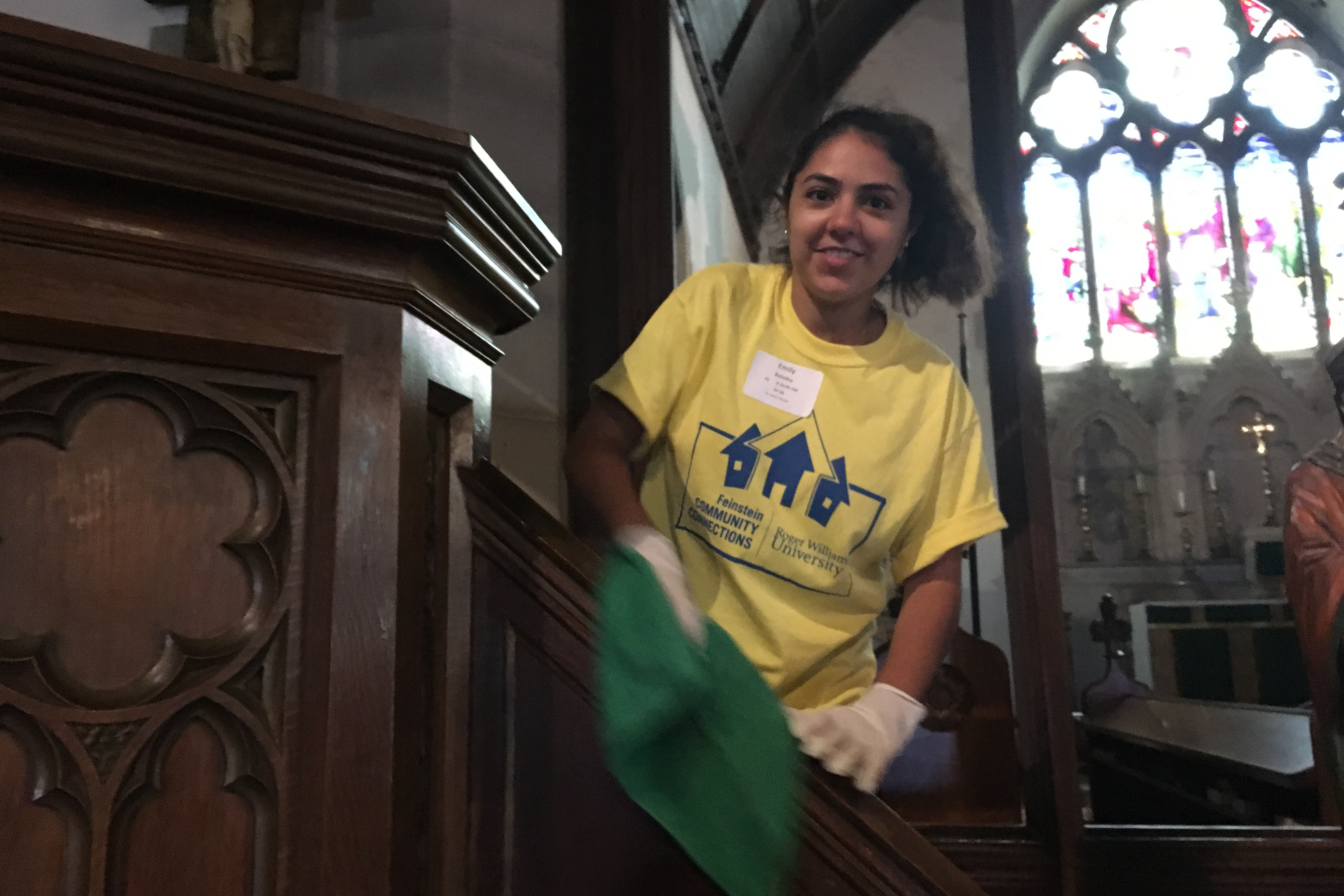 Student polishes woodwork inside church