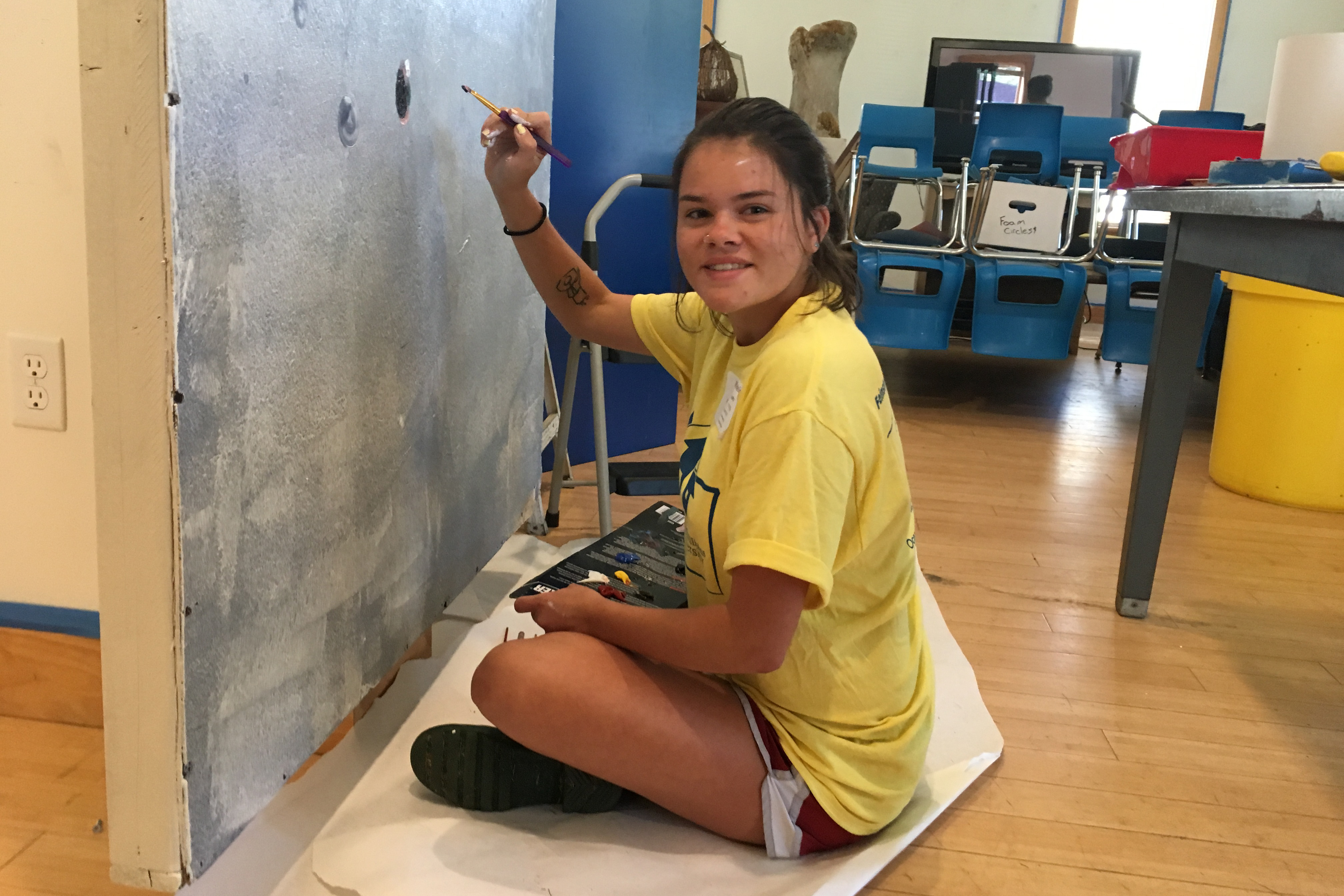 Student paints a mural on wall