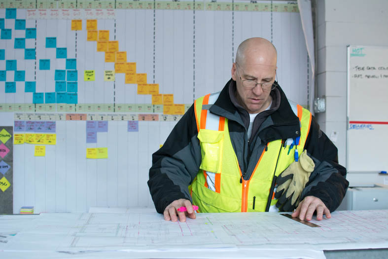 : Cameron in the Gilbane field office on Fountain Street in downtown Providence marks up layouts of the building.