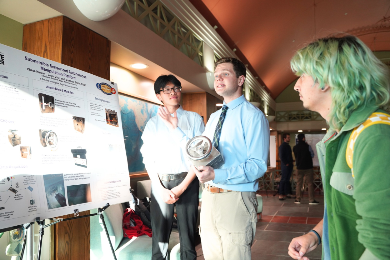 Seniors Chace Kirwan and Louis Zhu discuss their project with students at the Summer Research Showcase.
