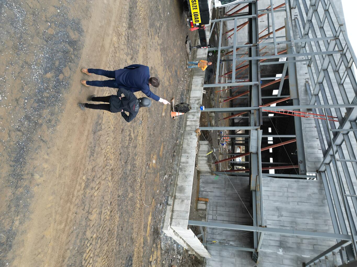 Crinieri, right, joins Baxter’s Director of Construction during a beam signing for a 40,000-square-foot food bank warehouse she completed in 2025.
