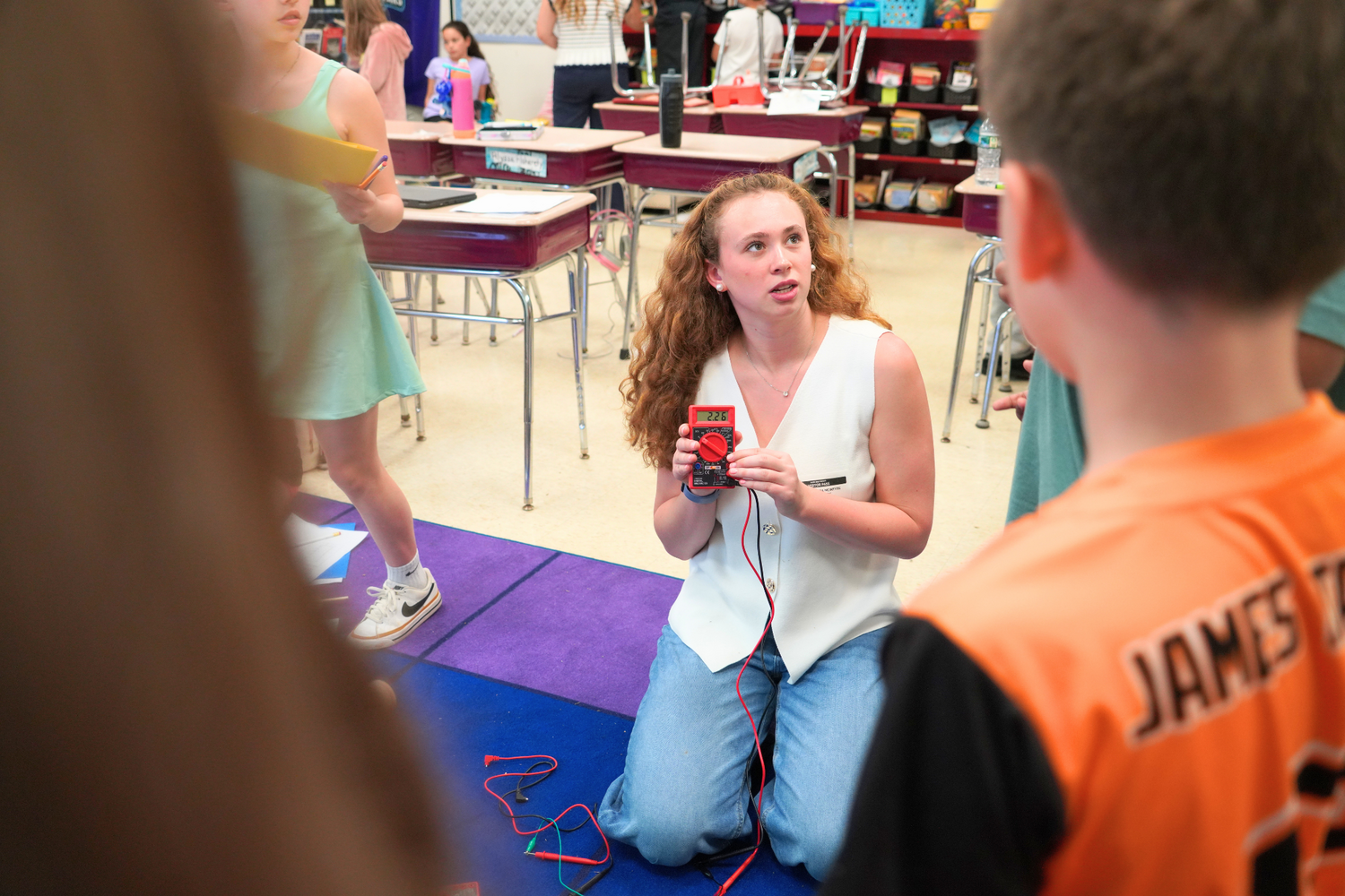 Sophomore Mattia McIntyre shows fourth graders how to use a multimeter to measure the electric output of their wind turbines.