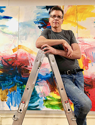 Michael Rich on a ladder in front of one of his abstract paintings. 