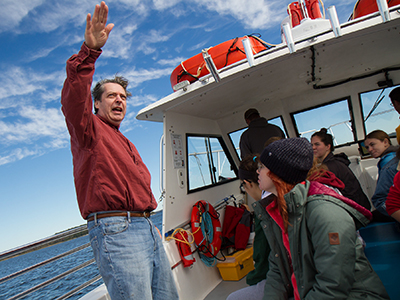 A professor on board a research vessel speaks to students 