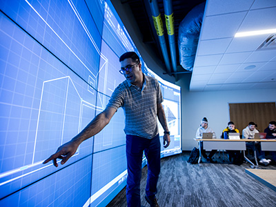 A professor showing a blueprint on a big screen in a classroom 