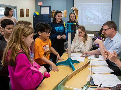 RWU students and elementary students in a classroom looking at a project about wind energy