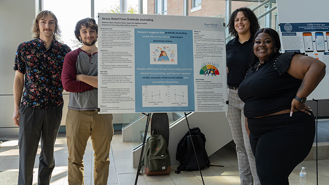 Four Psychology majors standing around their poster. 