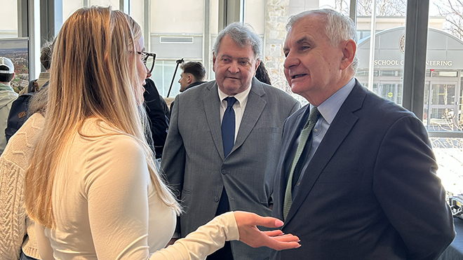 Senator Jack Reed and President Ioannis Miaoulis speak with a student