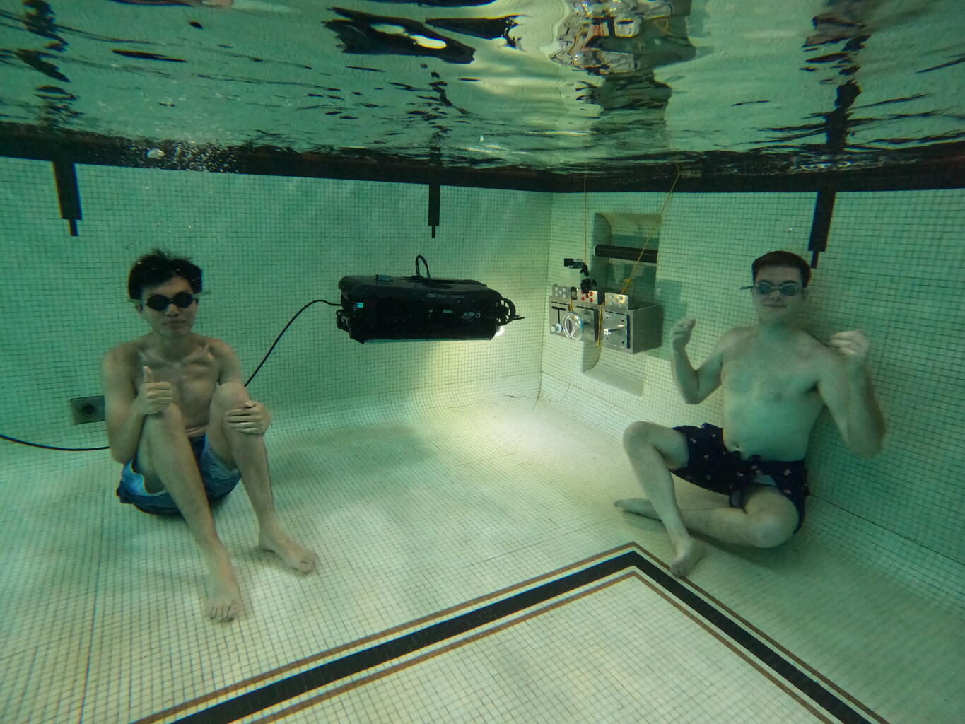 Seniors Chace Kirwan and Louis Zhu work underwater as a Deep Trekker robot tests its ability to complete tasks on their sensorized aluminum platform.