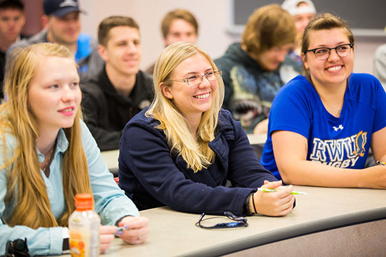 Students sitting in class smiling.