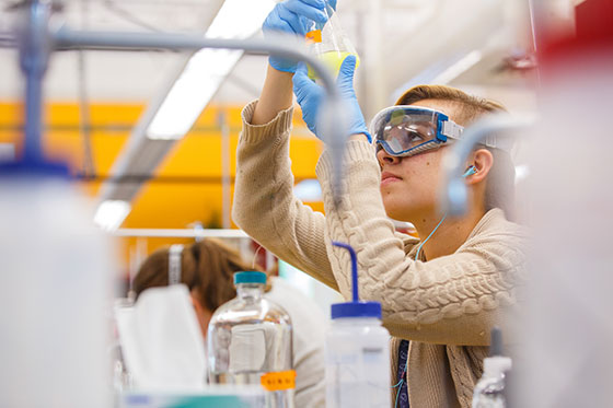 Student looking into beaker.