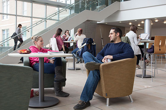 Professor talking with student in lounge.