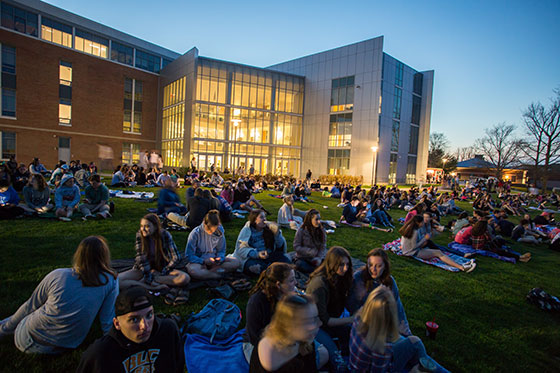 Students sitting on the lawn in front of GHH building.