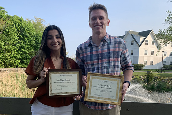 Two ANSOC graduates stand together holding certificates
