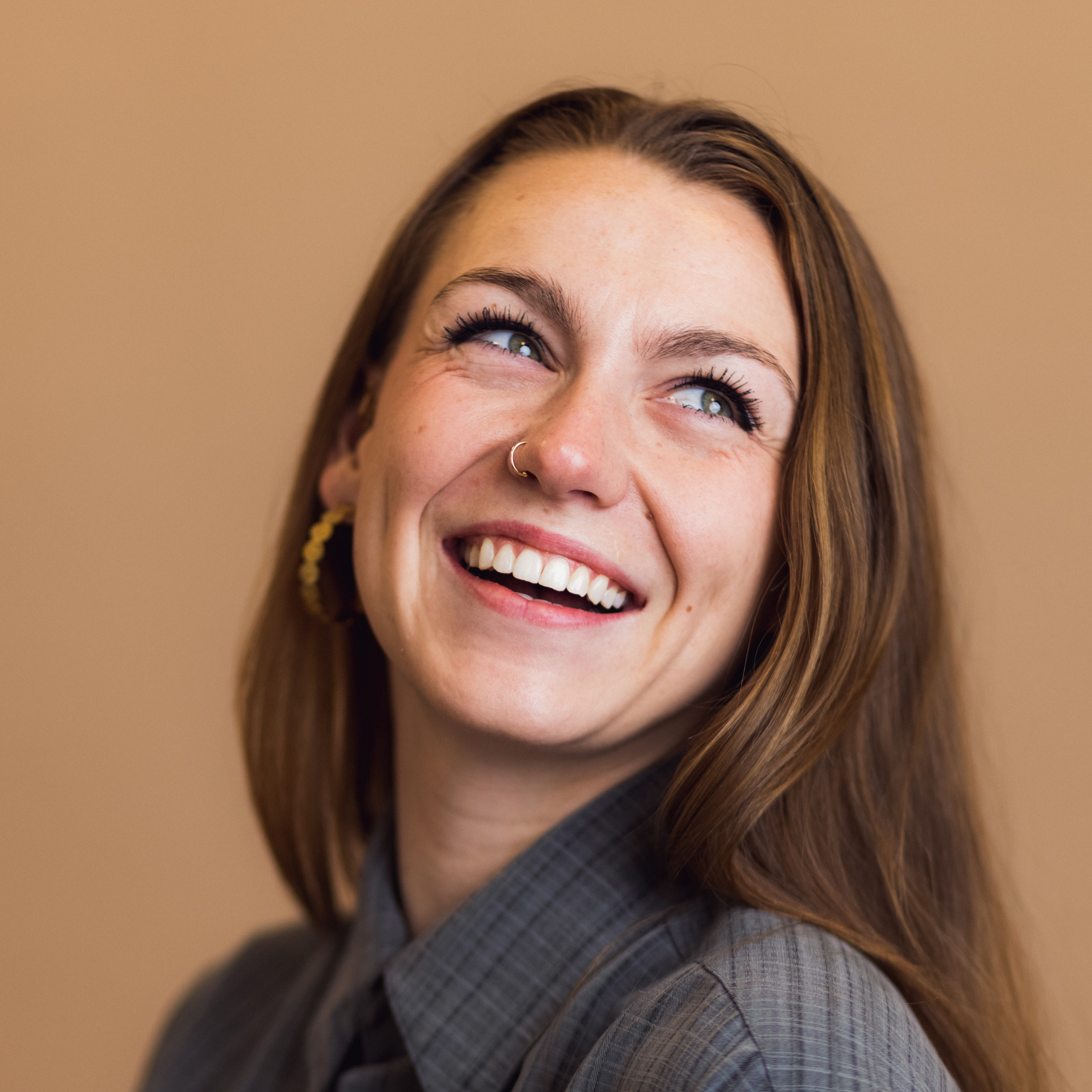 Smiling woman with long brown hair against a tan background