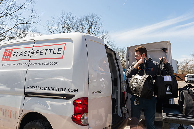 Feast and Fettle employee loads meals into a van.