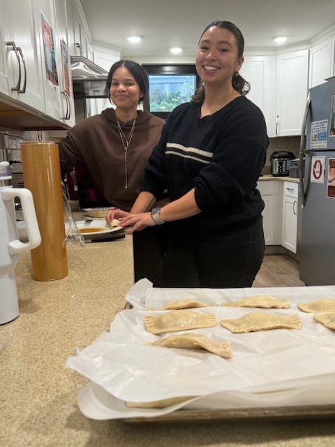 student and assistant director making empanadas in kitchen