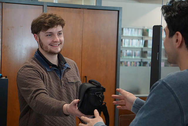 IT staff member handing camera bag to student