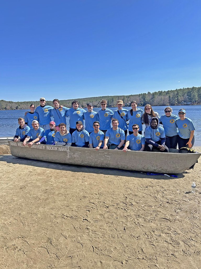2025 RWU Student Chapter of ASCE standing behind their concrete canoe on the banks of the river