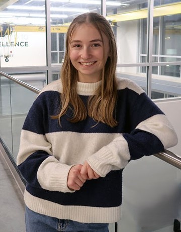 Maria Mangiameli smiling leaning against the railing on the second floor balcony of SELB