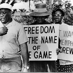 Marchers hold sign saying "Freedom Is The Name Of The Game" 