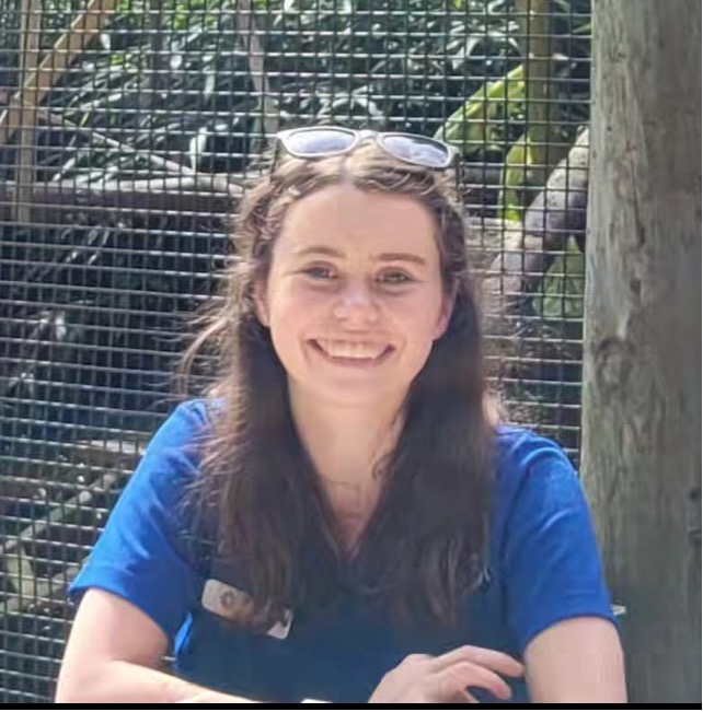 Becky Goyette smiling in a blue t-shirt in front of an animal enclosure.