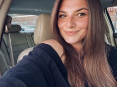 Katelyn Simeone smiling in a black shirt, sitting in an automobile.