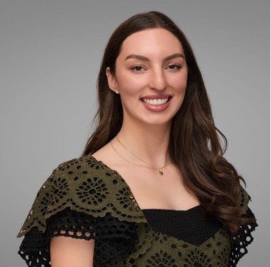 Talia Moine smiling in a black and green dress in front of a gray background.