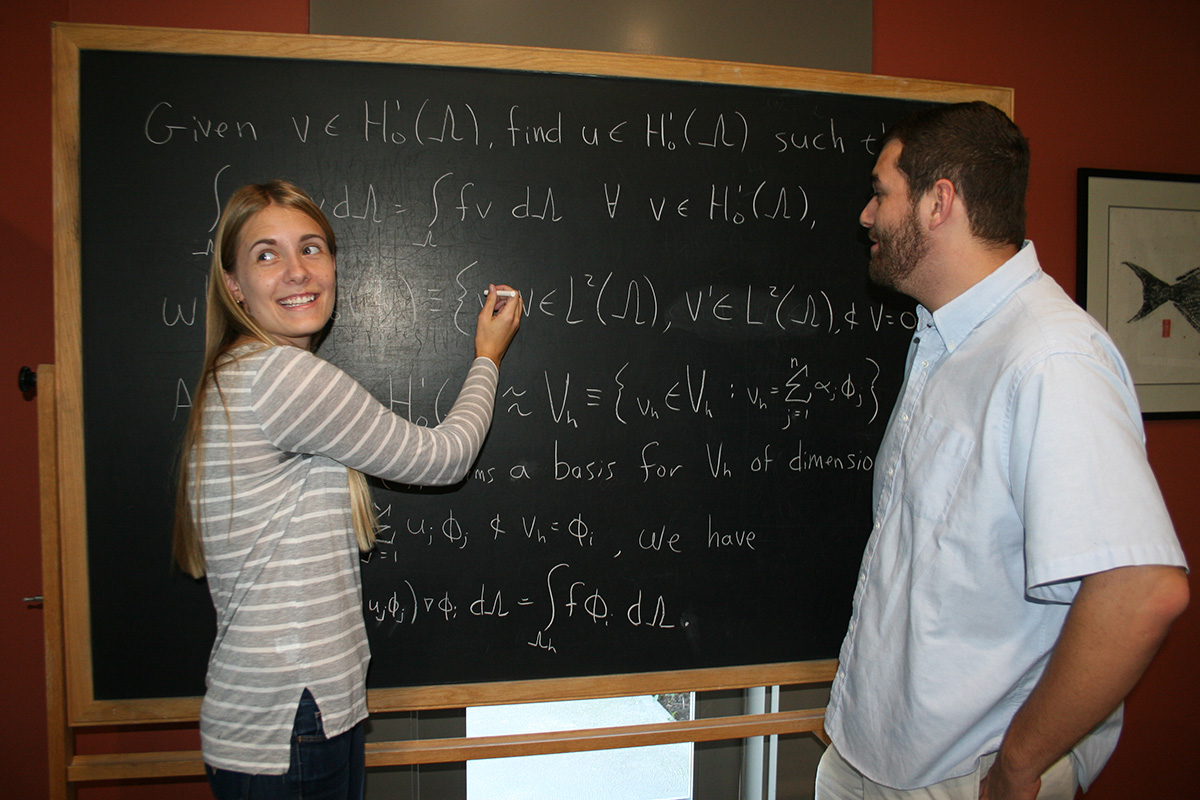 Students work on equation on blackboard.