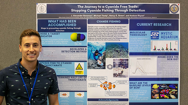 A photo of J. Alexander Bonanno ’17 with a poster of his research about testing for cyanide in marine fish