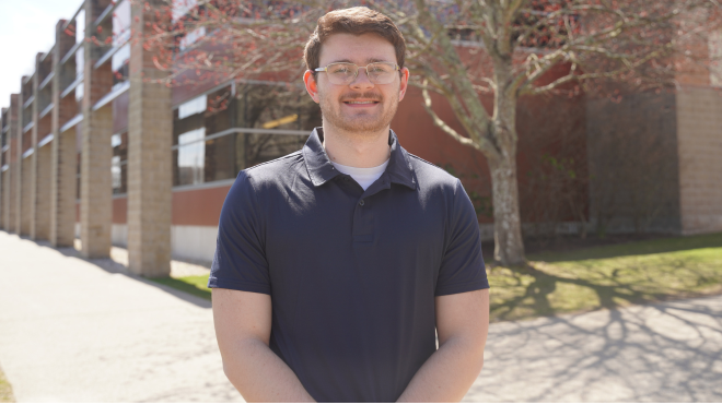 Sam Trieber standing in outside on a sunny day, smiling.