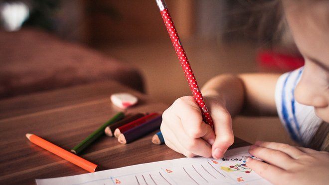 A young child writes in a classroom