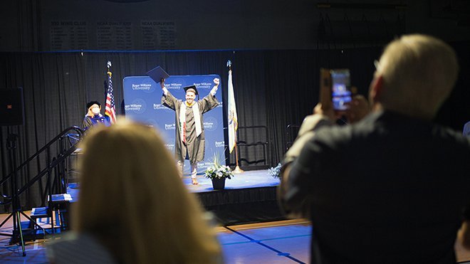 Graduate celebrates receiving his diploma on stage.