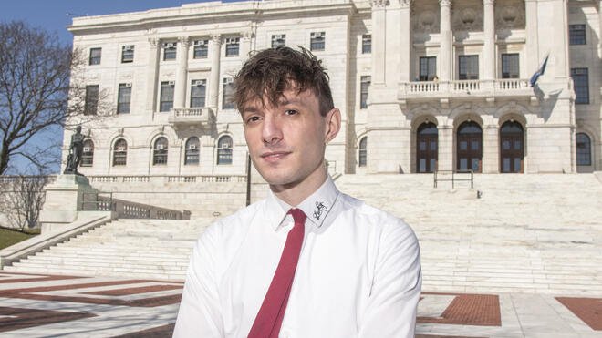 Alexander Castro stands outside the Rhode Island State House, where he frequently reports on the issues shaping the state’s future.