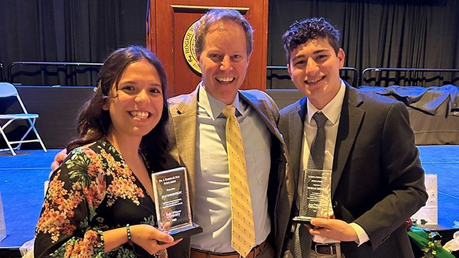 Derek Zuckerman with two students holding awards 