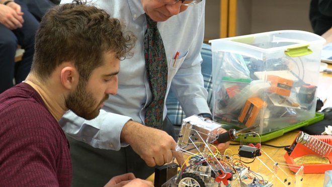 Engineering student repairs robot with help from Professor