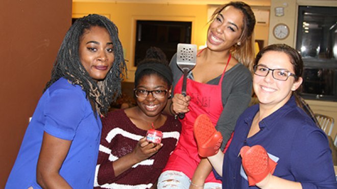 Four students holding spatulas and smiling.