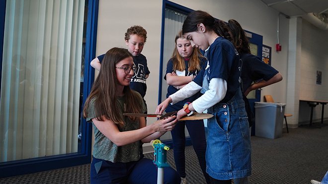 An RWU student helps fourth graders put together their wind turbine.