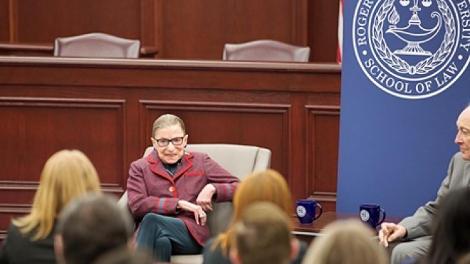 image of Supreme Court Justice Ruth Bader Ginsburg seated in a chair talking to students during her visit and 'fireside chat' at RWU Law in January 2018