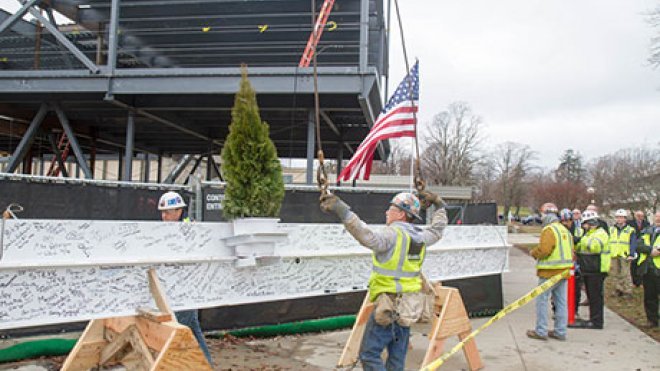 Construction crews prep the steel beam to be hoisted.