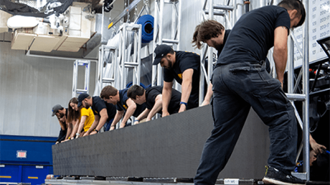 Stage Crew members hooking up lighting display.